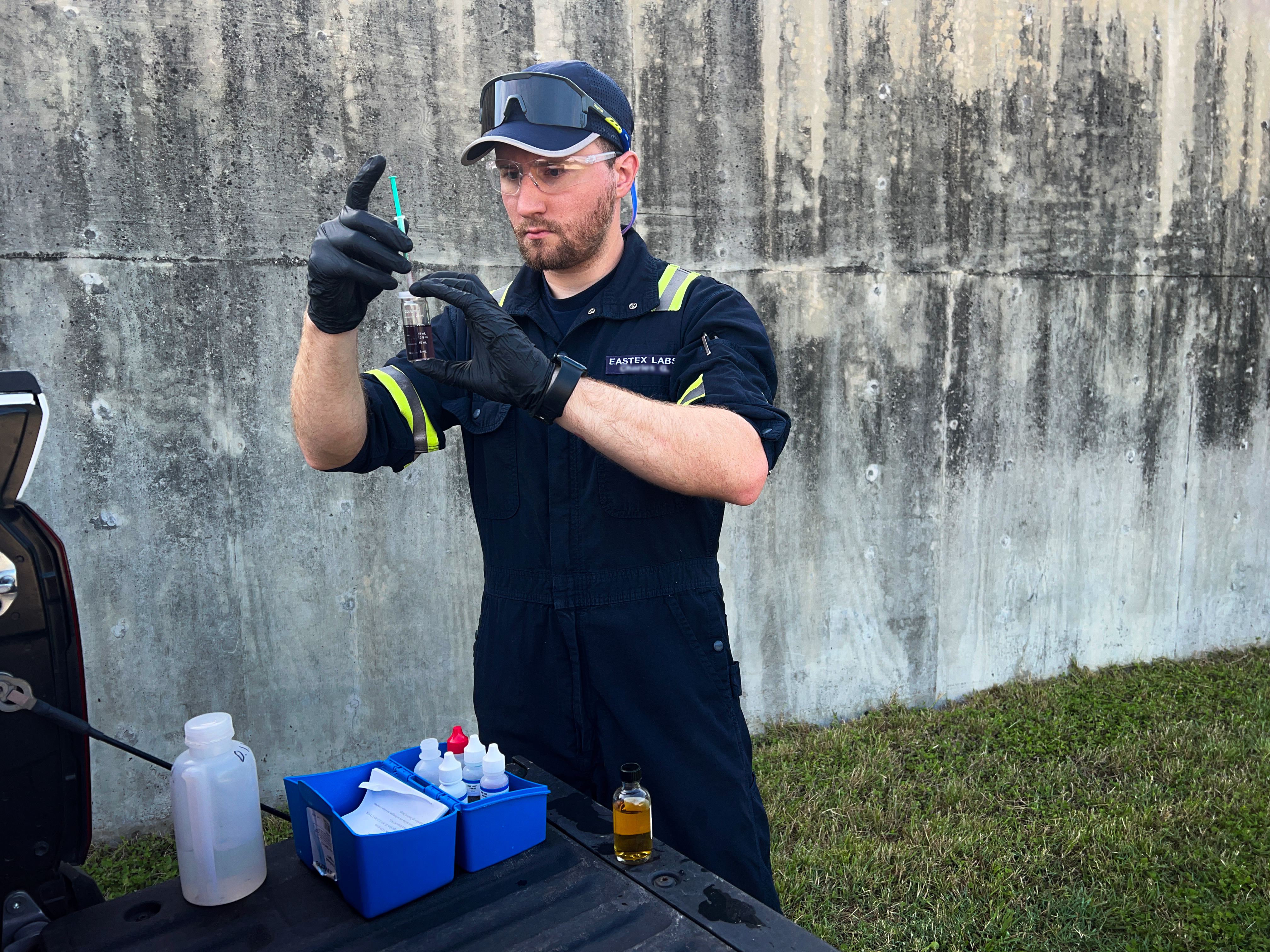 Eastex field technician collecting a sample at the back of a service truck