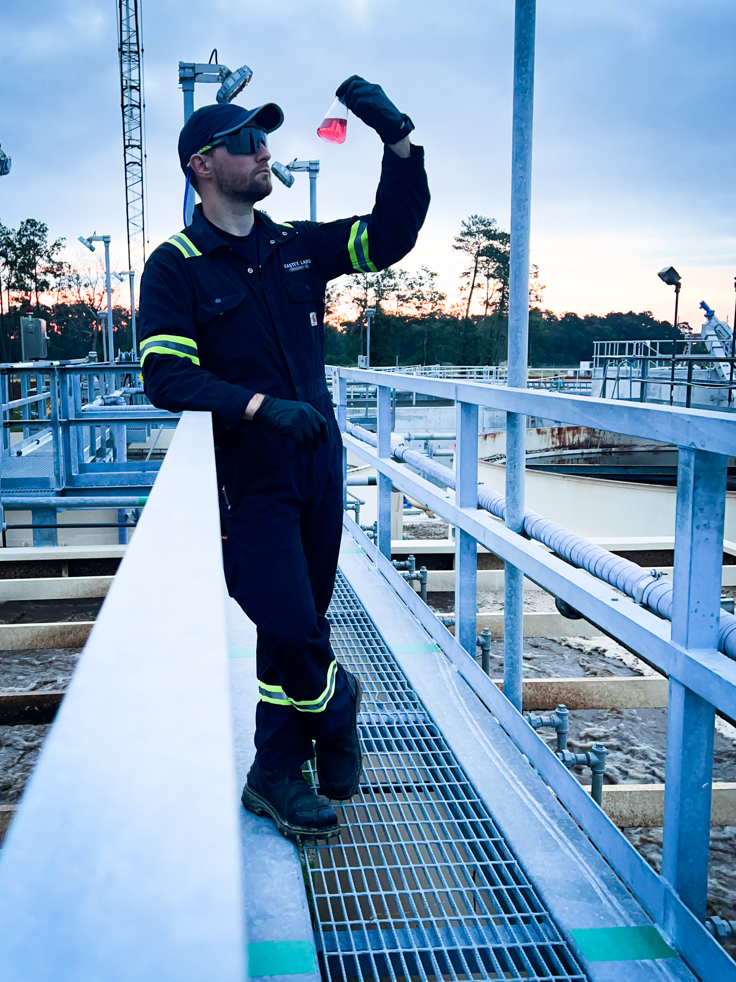 Eastex field technician inspecting a water sample at a Texas treatment plant at sunset