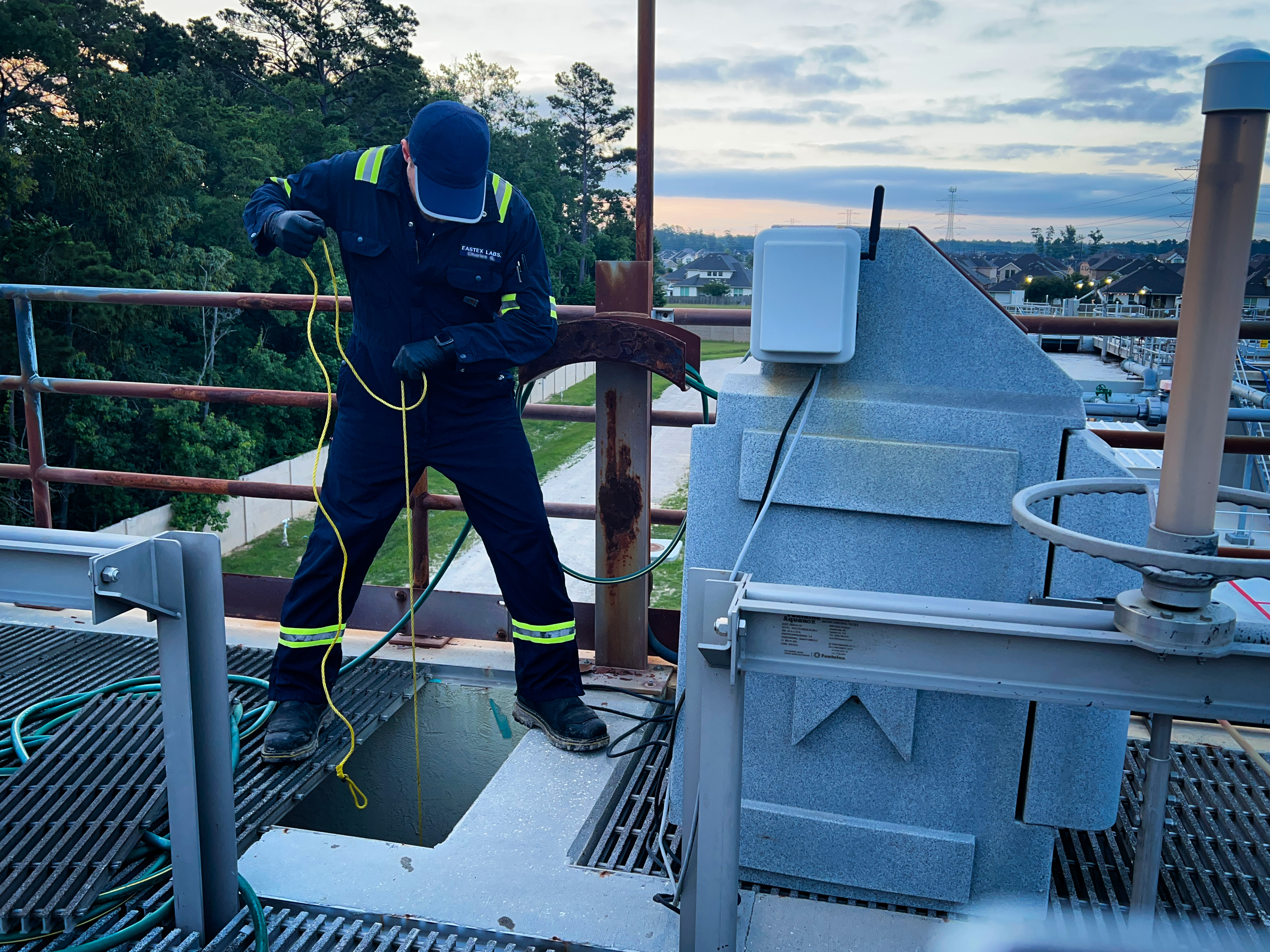Eastex field technician collecting a wastewater sample from a treatment plant hatch